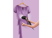 Charger l'image dans la galerie, Une personne repasse une blouse violette sur un cintre à l'aide d'un défroisseur à main noir et doré.