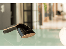 Charger l'image dans la galerie, Un défroisseur à main noir et cuivré sur une table en verre, avec un arrière-plan flou.