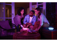 Charger l'image dans la galerie, Trois personnes autour d'une table, éclairées par des lumières violettes et bleues, et des bols.