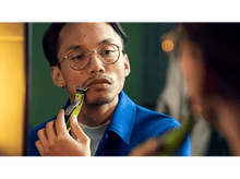 Charger l'image dans la galerie, Homme avec des lunettes se rase le visage avec un rasoir électrique Philips OneBlade vert et argenté.