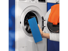 Charger l'image dans la galerie, Une main de femme tenant un tampon de nettoyage bleu près d'une machine à laver.