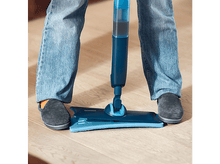 Charger l'image dans la galerie, Personne en jean et chaussons, utilisant une serpillière bleue sur un plancher en bois.