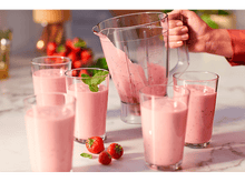 Charger l'image dans la galerie, Smoothie rose versé d'un blender dans des verres, avec des fraises.