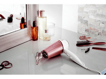 Charger l'image dans la galerie, Sèche-cheveux, miroir, bouteilles et accessoires sur une surface blanche.
