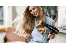 Charger l'image dans la galerie, Une femme sèche ses longs cheveux blonds avec un sèche-cheveux Philips.