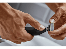 Charger l'image dans la galerie, Les mains d'une personne ajustent une tête de rasoir électrique noire et jaune.