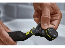 Charger l'image dans la galerie, Une main ajustant une tondeuse à barbe noire et jaune. La tondeuse a un cadran et une tête de coupe.