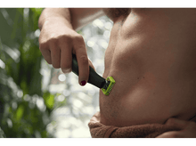 Charger l'image dans la galerie, Un homme se rase le corps avec un rasoir Philips OneBlade.