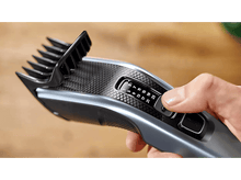 Charger l'image dans la galerie, Main ajustant les réglages d'une tondeuse à cheveux noire et grise.