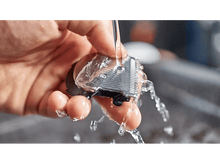 Charger l'image dans la galerie, Gros plan d'une main rinçant une tête de rasoir sous l'eau courante.