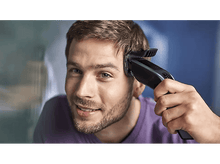 Charger l'image dans la galerie, Un homme se rase la tête avec une tondeuse à cheveux Philips noire, souriant à la caméra.
