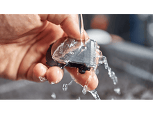 Charger l'image dans la galerie, Une main lavant une tête de rasoir Philips sous l'eau courante. Gros plan.