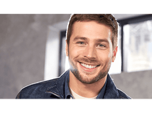 Charger l'image dans la galerie, Un homme souriant avec des cheveux bruns courts et une barbe, portant une veste en jean, regardant la caméra.