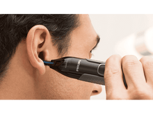 Charger l'image dans la galerie, Un homme qui taille les poils des oreilles avec une tondeuse Philips. Gros plan.