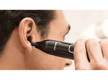 Charger l'image dans la galerie, Un homme utilise un rasoir nasal Philips noir et bleu près de son oreille.