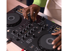 Charger l'image dans la galerie, Les mains d'une personne manipulent une table de mixage DJ avec des boutons et des boutons visibles.