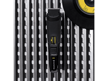 Charger l'image dans la galerie, Tondeuse Remington noire avec détails jaunes sur une surface métallique, à côté d'un disque vinyle.