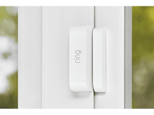 Charger l'image dans la galerie, Un détecteur de porte Ring blanc est fixé à une porte blanche. L'arrière-plan est vert flou.