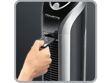 Charger l'image dans la galerie, Main tenant une télécommande vers un ventilateur tour noir et argent.