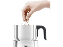 Charger l'image dans la galerie, Main versant des flocons sur un mousseur à lait argenté. Le mousseur est sur un fond blanc.