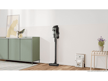 Charger l'image dans la galerie, Un aspirateur noir debout. Il est à côté d'un meuble.