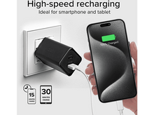 Charger l'image dans la galerie, Un téléphone se charge avec un chargeur noir branché au mur, affichant 100% chargé.