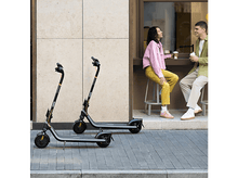 Charger l'image dans la galerie, Deux scooters garés sur un trottoir. Un couple est assis à une table en arrière-plan.