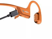 Charger l'image dans la galerie, Casque Shokz orange avec câble de chargement branché sur fond blanc.