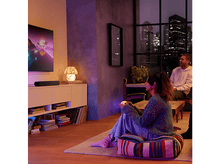 Charger l'image dans la galerie, Couple regardant la télévision dans une pièce avec un éclairage coloré. Barre de son en dessous.