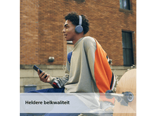 Charger l'image dans la galerie, Jeune homme avec un casque et un téléphone. Il est dehors, avec un bâtiment en briques.