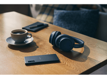 Charger l'image dans la galerie, Casque, téléphone, bloc-notes et café sur une table en bois.