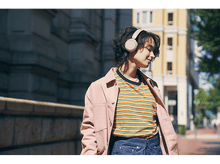 Charger l'image dans la galerie, Jeune femme en casque audio marchant dans une rue de la ville, portant une veste rose.