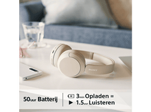 Charger l'image dans la galerie, Casque beige sur une table, à côté d'un téléphone et d'un verre d'eau. Le texte indique la durée de vie de la batterie.