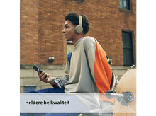 Charger l'image dans la galerie, Jeune homme avec un casque, tenant un téléphone, devant un mur de briques.