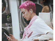 Charger l'image dans la galerie, Homme aux cheveux roses écoutant de la musique avec des écouteurs verts, regardant son téléphone.