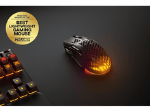 Charger l'image dans la galerie, Une souris de jeu avec éclairage RVB sur une surface sombre, à côté d'un clavier.