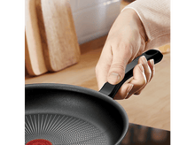 Charger l'image dans la galerie, Une personne tenant une poêle noire avec un cercle rouge.