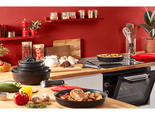 Charger l'image dans la galerie, Scène de cuisine avec de la nourriture dans des poêles sur un comptoir en bois. Mur rouge en arrière-plan.