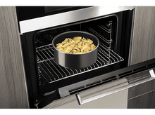 Charger l'image dans la galerie, Un four avec la porte ouverte, montrant une poêle ronde avec des pâtes et des légumes à l'intérieur.
