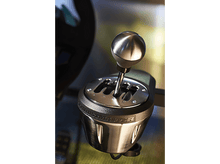 Charger l'image dans la galerie, Gros plan d'un levier de vitesse de voiture. Boule argentée sur socle noir, avec marquages d'engrenages.