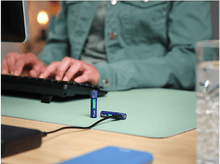 Charger l'image dans la galerie, Deux piles bleues Trust. et un clavier sur un bureau vert.