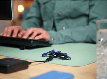 Charger l'image dans la galerie, Personne tape sur un clavier. Piles rechargeables et câble de charge sur le bureau.