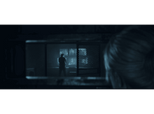 Charger l'image dans la galerie, Une femme regarde un homme dans une pièce à travers une fenêtre. L'homme est dans une pièce avec des moniteurs.