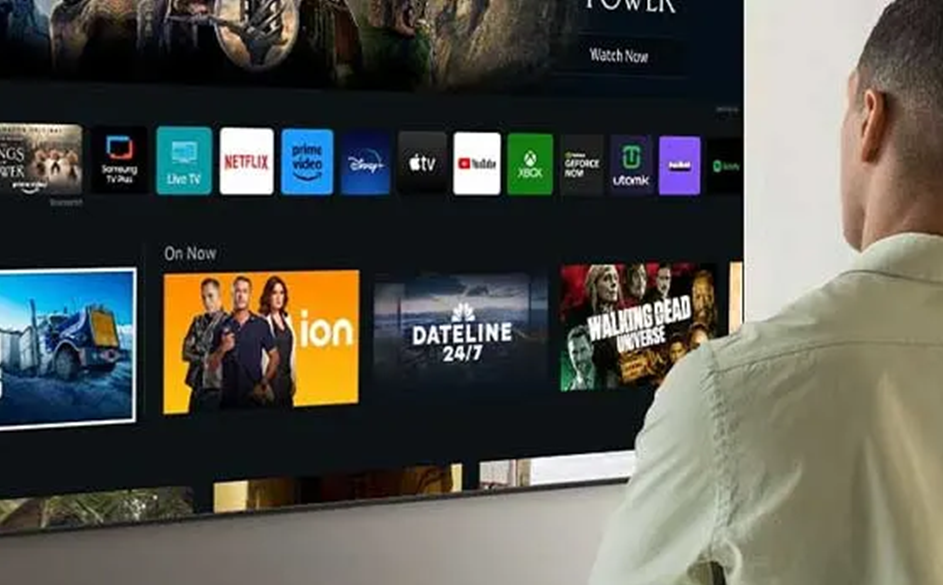 Un homme de dos regarde l'écran d'accueil de sa Smart TV.