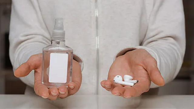 Une personne tend les mains ouvertes. Dans une main se trouve une paire d'AirPods et dans l'autre un produit nettoyant.