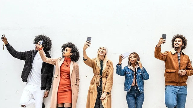 Un groupe de personne se prend en selfie devant un mur un blanc
