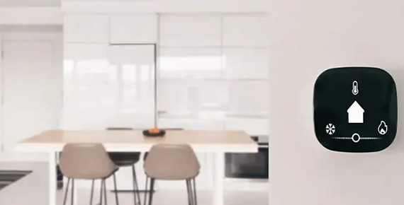 Photo d'un thermostat connecté fixé sur le mur d'une cuisine.