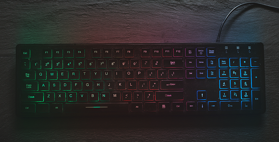 Un clavier gamer avec des touches rétroéclairées multicolores posé sur un bureau.