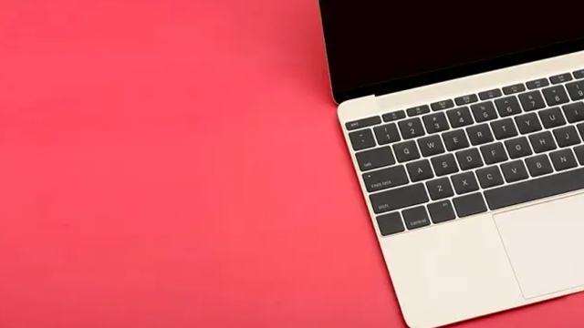 Une parte d'un écran d'ordinateur portable et de son clavier sur un fond rouge.