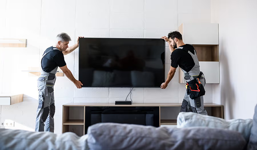 deux hommes installent fixe une tv à mur  blanc dans une pièce de vie.